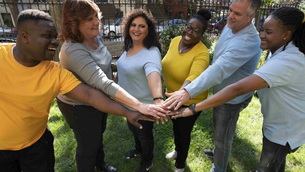 People in a park putting their hands into the middle of the group