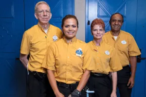 Workers in yellow shirts in front of a blue door