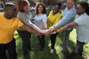 People in a park putting their hands into the middle of the group